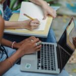 crop faceless diverse students working on assignment together in park