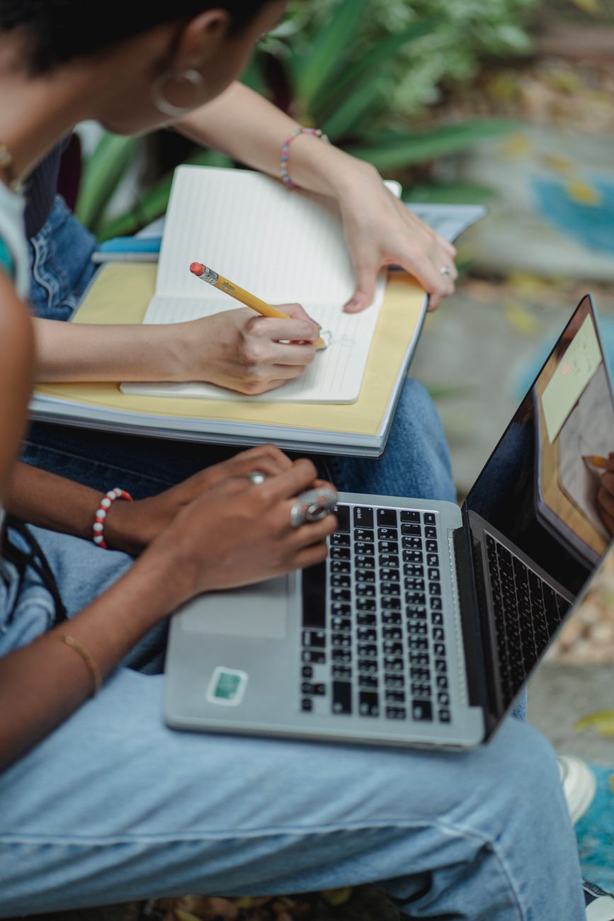 crop faceless diverse students working on assignment together in park